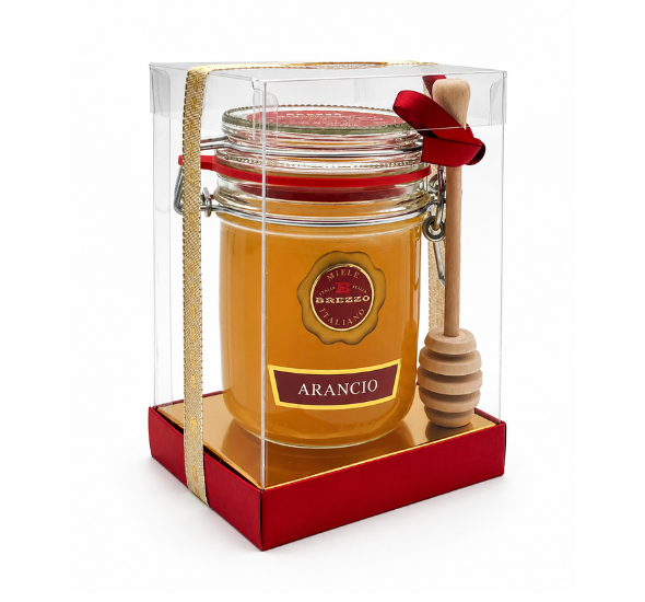 Gift-wrapped jar of orange honey with a wooden honey dipper in a clear box and red base.