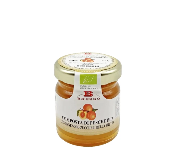 Small glass jar of organic peach compote with a gold lid and label 'Composta di Pesche Bio'.